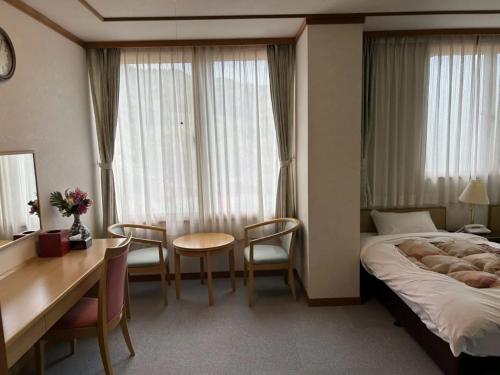 魚沼市にある浅草山荘のベッド、テーブル、椅子が備わるホテルルームです。