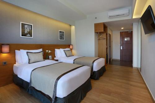 a hotel room with two beds and a television at Azana Boutique Hotel Denpasar in Denpasar