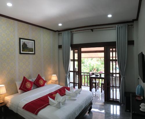 a bedroom with a large bed and a balcony at Luang prabang KhounSok Sunset villa in Luang Prabang