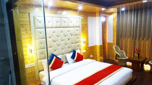 a bedroom with a large bed with red and blue pillows at Humble Holiday Home Kufri S H I M L A with Lawn and Amazing View in Kūfrī