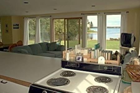 a kitchen with a stove and a living room at Dorsey in Deer Isle