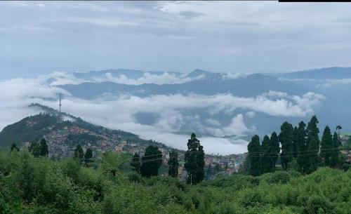 a view of a city on a hill with clouds at K - Den Homestay in Kurseong