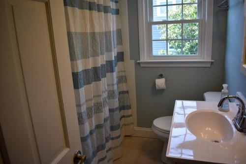 a bathroom with a sink and a toilet and a window at Seaside Serenity, just a block /0.1 mile away from the beach in Yarmouth