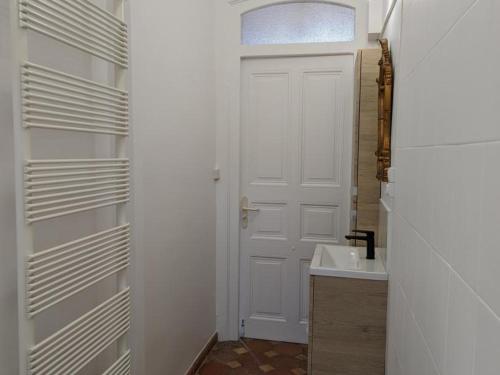 La salle de bains est pourvue d'une porte blanche et d'un lavabo. dans l'établissement Charmant gîte familial avec piscine chauffée, parc et animaux - 3 chambres, internet, équipements bébé - FR-1-653-233, à Chadurie