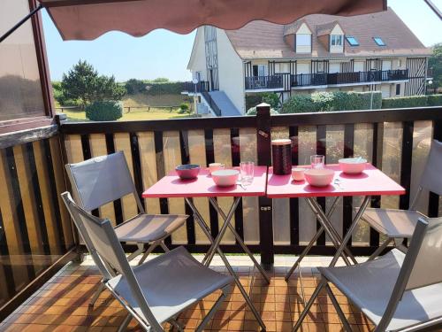 une table et des chaises roses sur un balcon avec vue dans l'établissement Duplex en front de mer avec balcon à Merville-Franceville-Plage - FR-1-465-99, à Merville-Franceville-Plage