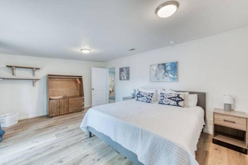 a bedroom with a white bed and a wooden floor at Charming Modern 3BR Fresno House in Fresno
