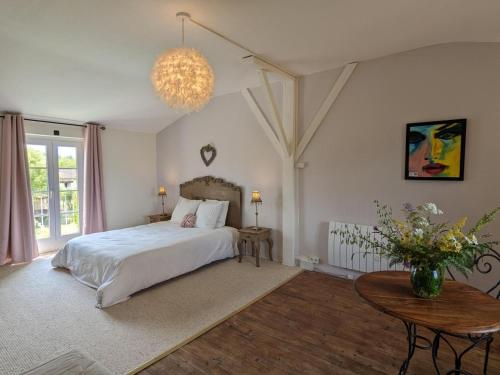 une chambre avec un lit, une table et un lustre dans l'établissement Petit gîte romantique avec piscine couverte, jardin et animaux, proche de la nature à Chadurie - FR-1-653-234, à Chadurie