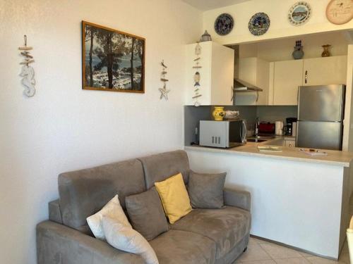 un salon avec un canapé et une cuisine dans l'établissement Appartement climatisé en bord de mer, Le Lavandou - FR-1-308-181, au Lavandou