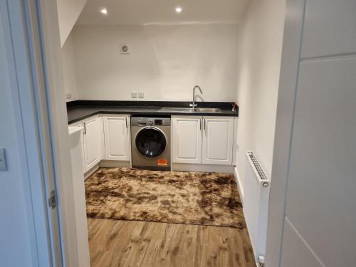 a kitchen with a sink and a washing machine in it at A Spacious and Hearty 2BD Swindon stay in Swindon