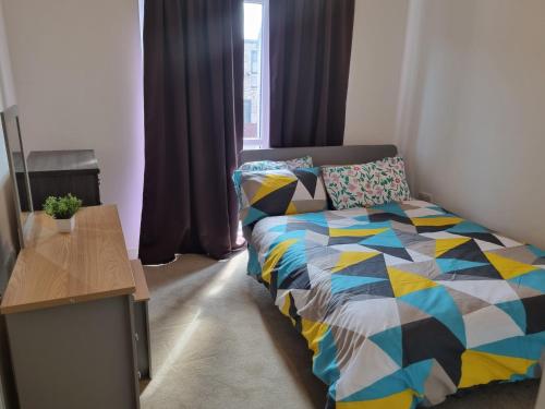 sypialnia z łóżkiem z kolorową kołdrą w obiekcie A Spacious and Hearty 2BD Swindon stay w mieście Swindon