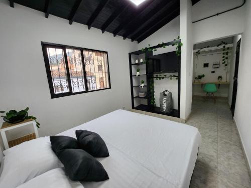 una camera da letto con un letto bianco e cuscini sopra di PRADO DOWNTOWN a Medellín