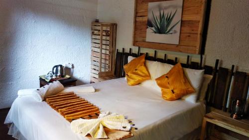 1 dormitorio con 1 cama blanca grande con almohadas amarillas en Elephant Trail Guesthouse and Backpackers, en Kasane