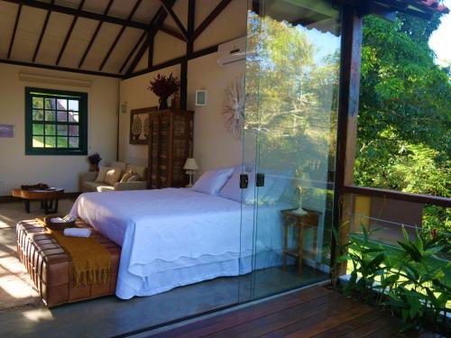 Lofts Villa da Serra في تيرادينتيس: غرفة نوم بسرير وجدار زجاجي