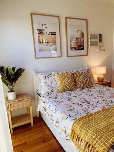 a bedroom with a bed and two pictures on the wall at Port Douglas Beach Cottage in Port Douglas