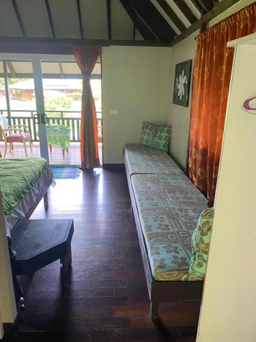 a living room with two beds and a balcony at Pension Reva Teahupoo in Toanoano