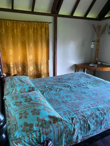 a bedroom with a bed with a blue comforter at Pension Reva Teahupoo in Toanoano