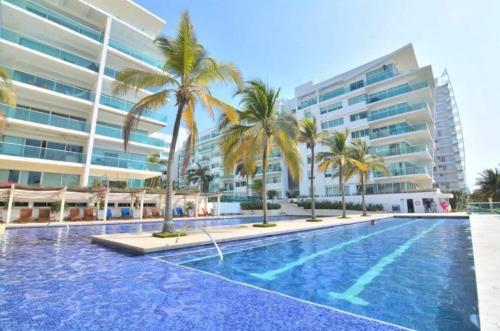 een zwembad met palmbomen voor een gebouw bij Cartagena Beach Apartment - Salida Directa Al Mar in Cartagena