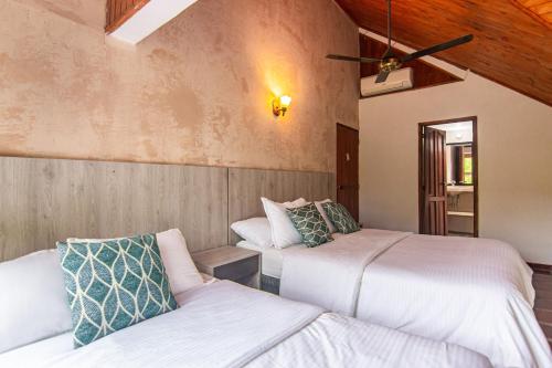 a bedroom with two beds and a ceiling fan at Portales del Tayrona Garden Hotel in Calabazo