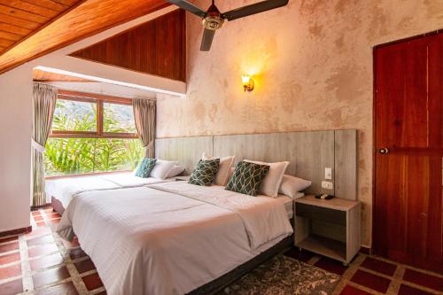 een slaapkamer met 2 bedden en een raam bij Portales del Tayrona Garden Hotel in Calabazo