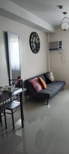 a living room with a couch and a clock on the wall at CEBU Simple Condominium in Cebu City
