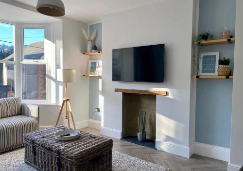 sala de estar con TV y chimenea en ‘Sandy Bottom’ - Apartment by the sea, en Combe Martin
