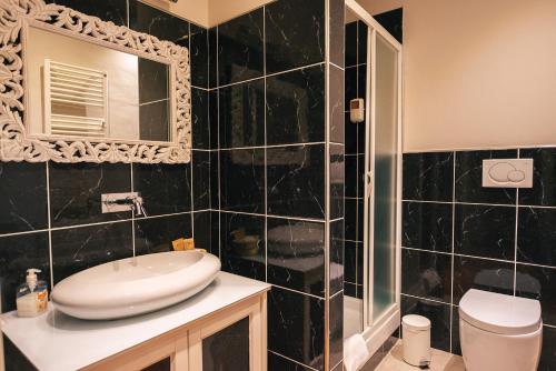uma casa de banho em azulejos pretos com um lavatório e um espelho. em Boutique Hotel Casa Grimaldi em Matelica