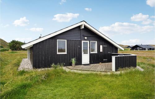a black house with a wooden deck in a field at Amazing Home In Ringkøbing With Sauna in Ringkøbing