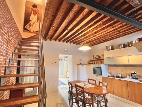 uma cozinha e sala de jantar com uma mesa de madeira e uma escada em Boutique House Alle Loggie Palladiane di Villa Contarini em Piazzola sul Brenta