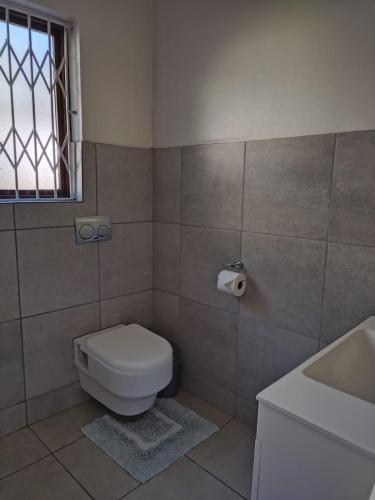 a bathroom with a toilet and a sink and a window at 19 Mirabelle Place in Pietermaritzburg