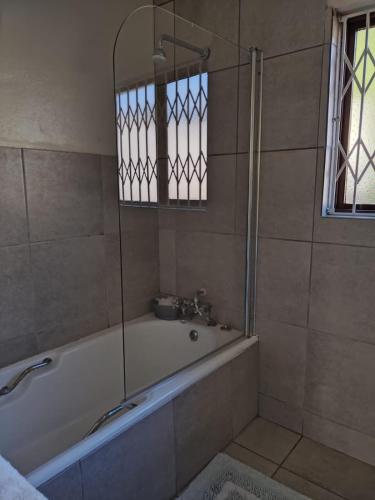 ein Bad mit einer Badewanne und einer Dusche mit einem Fenster in der Unterkunft 19 Mirabelle Place in Pietermaritzburg