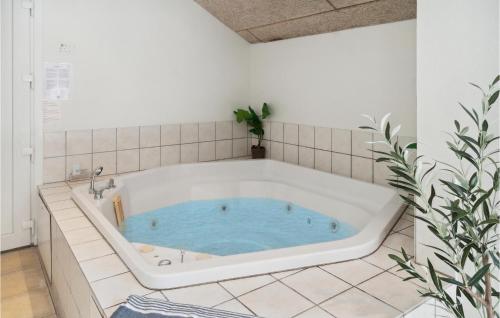 DannemareにあるAmazing Home In Dannemare With 7 Bedrooms, Sauna And Wifiのバスルーム(青い水を使用したバスタブ付)