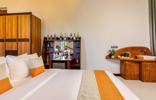 a bedroom with a bed and a shelf with bottles at The Palace by Ocean in Bentota