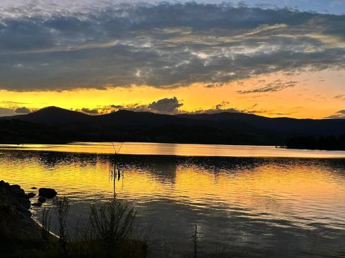 a sunset over a lake with mountains in the background at Carinya Village Jindabyne in Jindabyne