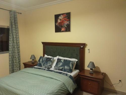 una camera da letto con un letto con un piumone verde e due lampade di Lydie's Home a Yaoundé