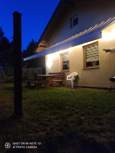 a house with a picnic table and a bench at night at Słonik in Stegers