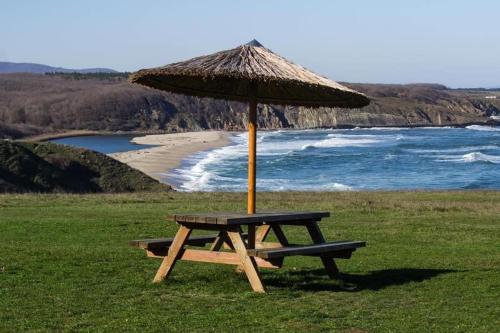 a picnic table with an umbrella on the beach at Каравана в Синеморец in Sinemorets