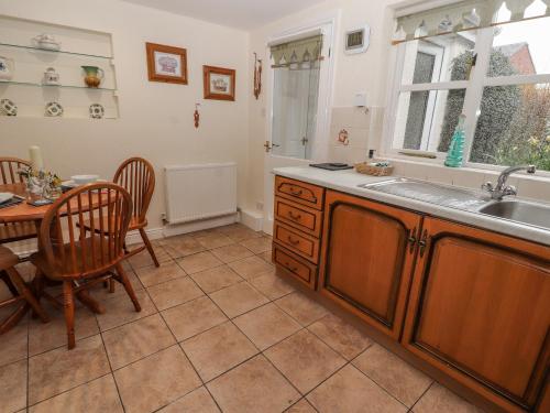 cocina con mesa, fregadero, mesa y sillas en Bryn Offa cottage en Holywell