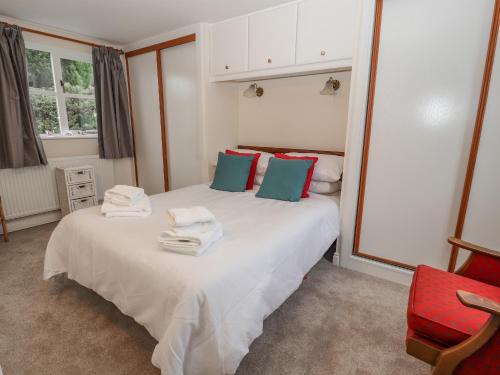 um quarto com 2 camas e uma cadeira vermelha em Bryn Offa cottage em Holywell