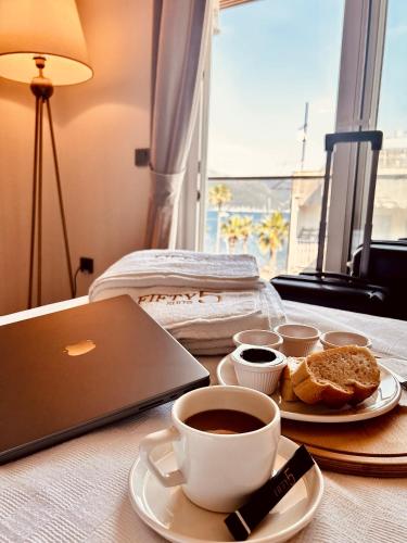 a table with a laptop and cups of coffee and bread at FİFTY5 SUİTE HOTEL in Marmaris