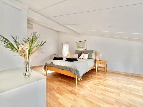 ein weißes Schlafzimmer mit einem Bett und einer Vase darauf in der Unterkunft Jolie maison familiale in Valbonne