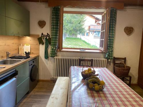 une cuisine avec une table avec un bol de fruits dessus dans l'établissement Chalet LA SOURCE, à Cohennoz