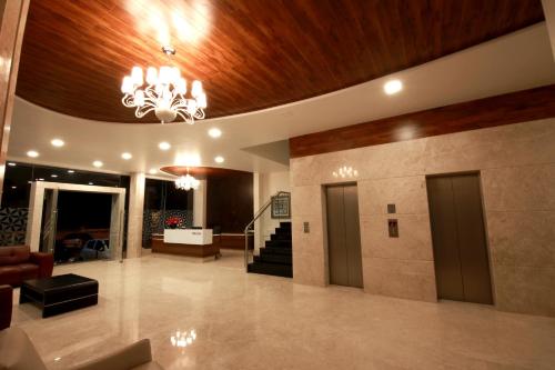 a lobby with a chandelier and stairs in a building at Palguni Residency in Hassan