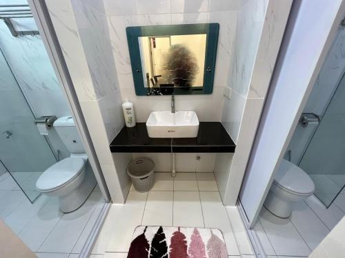 W łazience znajduje się umywalka, toaleta i lustro. w obiekcie One Point Hotel @ King Centre w mieście Kuching