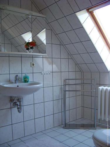 ein weiß gefliestes Bad mit einem Waschbecken und einem WC in der Unterkunft Haus Fledermaus in Bad Schmiedeberg