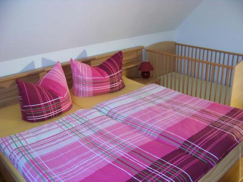 ein Bett mit vier rosa Kissen darüber in der Unterkunft Haus Fledermaus in Bad Schmiedeberg