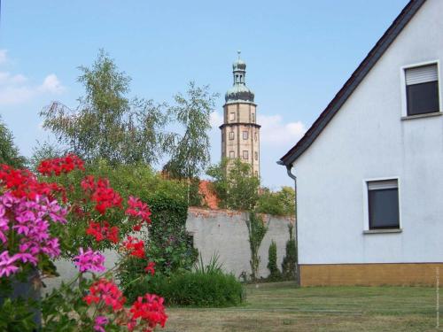 ein weißes Haus mit einem Uhrturm im Hintergrund in der Unterkunft Haus Fledermaus in Bad Schmiedeberg