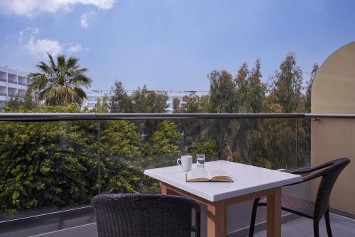 een tafel met een boek en twee stoelen op een balkon bij The Apartments by Esperia in Rhodos-stad
