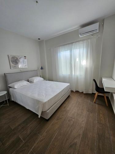 sypialnia z dużym białym łóżkiem i biurkiem w obiekcie Meliti w Lixoúrion