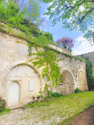 an old stone wall with a large door and ivy at Domaine Le Clos de la Source - Spa - Petit déjeuner buffet - Atelier d'art in Montrichard