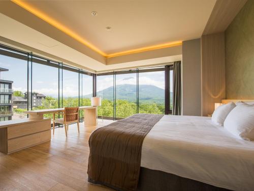 a bedroom with a large bed and a desk and windows at Aya Niseko in Niseko